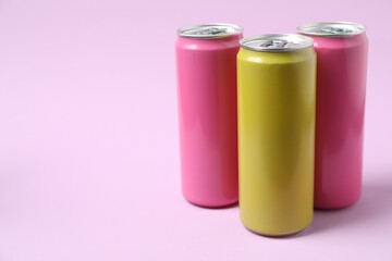 Three tin cans on light pink background. Space for text