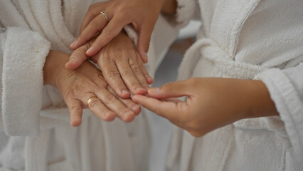 Mother and daughter bonding at a wellness spa wearing robes while holding hands in a serene interior setting