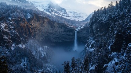 Frozen mountain waterfall framed by snowy cliffs, thick fog rolling through the valley, early morning light piercing the cold