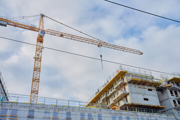 Unfinished concrete multi story building under construction with scaffolding and cranes. Modern urban development, contemporary architecture and construction industry concept