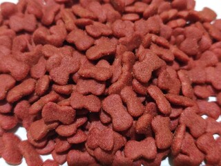 cat food background. dry, bone-shaped cat food in a reddish-brown color. It has a rough texture with small granules, making it suitable as crunchy kibble for cats.