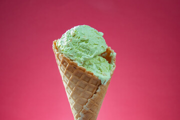 Ice cream cone with colorful sprinkles on pink background, close up