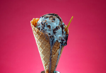 Ice cream cone with colorful sprinkles on pink background, close up