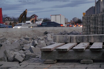 close-up pedestrian road or sidewalk renovation, building from scratch in the evening. Stones, sand and tiles