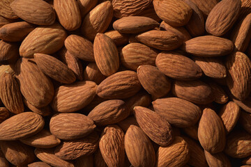 Photograph of dried almonds nuts in contrast lighting. Top view  almonds background. Healthy eating and snack, whole foods. Source of protein and magnesium.