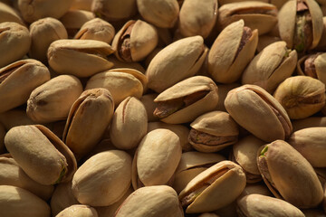 Close up photograph of roasted and salted pistachio nuts in contrast light and selective focus. Healthy eating, whole foods. 