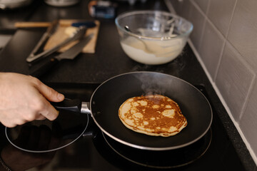 A close-up shot of a man flipping a pancake on a frying pan