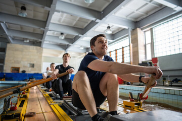 Focused strong suffocating rower leader and crew use paddle on kayak water simulator in pool. Sportive team prepares for competitions, championship, coordination and collaborative effort, active hobby © DimaBerlin