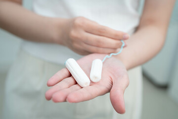Asian woman holding cotton tampons for hygiene menstrual period cycle protection.