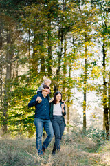 Dad with a little girl on his shoulders walks hugging mom in the park