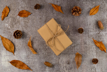 Gift box with autumn leaves,cones,acorns on a gray background. Flat lay, top view.