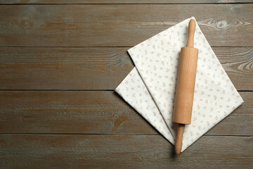Rolling pin and napkin on wooden table, top view. Space for text