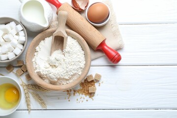 Rolling pin and ingredients for dough on white wooden table, flat lay. Space for text