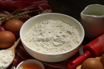 Rolling pin and ingredients for dough on table, closeup