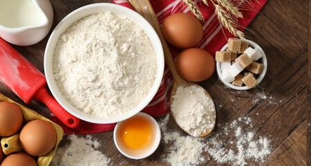 Rolling pin and ingredients for dough on wooden table, flat lay