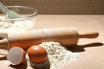 Rolling pin, flour and egg on wooden table