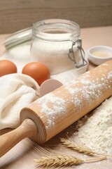 Rolling pin, flour and eggs on wooden table, closeup
