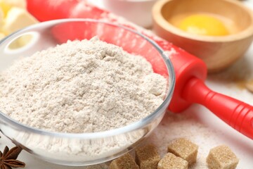 Rolling pin and different ingredients on white table, closeup