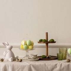 Creative composition of easter living room interior with copy space, vase with spring tulips, easter bunny sculpture, elegant cup, colorful easter eggs and personal accessories. Home decor. Template.
