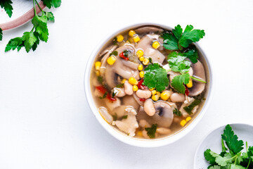 Spicy soup with chicken, mushrooms, corn, white beans, chili and cilantro. White background, top view