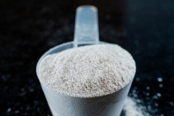 White powder in a scoop on a dark surface close-up