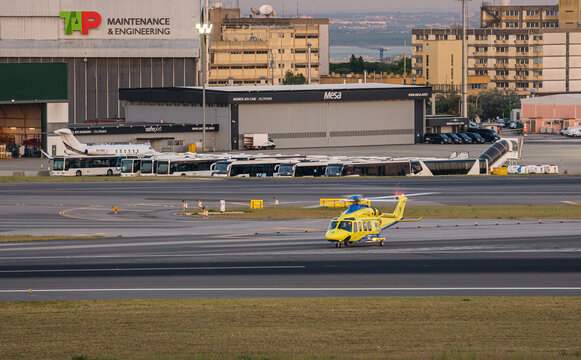 Yellow rescue helicopter on taxiway near TAP Maintenance hangar at