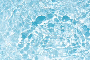Obraz premium Blue water with ripples on the surface. Defocus blurred transparent blue colored clear calm water surface texture with splashes and bubbles. Water waves with shining pattern texture background.