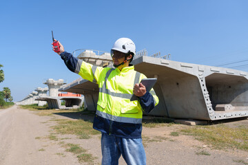 Asian architect engineer wearing safety uniform surveying and working at building structure checking blueprints construction site road general job details business concept architecture street