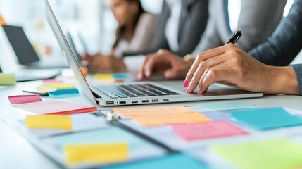 A collaborative workspace with individuals using laptops and colorful sticky notes for brainstorming and planning.
