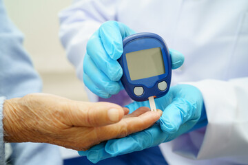 Asian doctor using digital glucose meter for check sample blood sugar level to treatment diabetes.