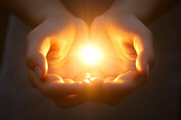 Two hands holding together with sunlight shining through, symbolizing unity and warmth