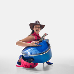 Cowgirl in vibrant outfit crouching with blue guitar, strumming with confidence and deep connection...