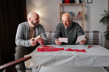 Happy senior father and son preparing birthday decorations at home