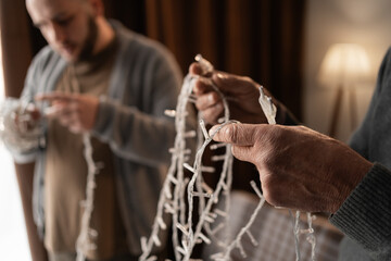 Father and son untangling decorative string lights for a party