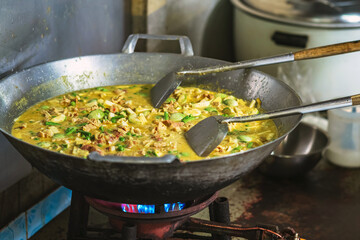 Pork fillet in a spicy coconut sauce green curry in a large cooking pan on stove. Green curry with pork.  Thai cuisine. Vegetable pan, Pork pan, Thai curry with fresh vegetables and meat in a wok pan.