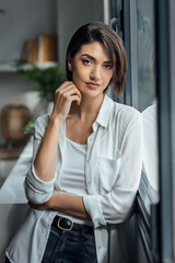 Fototapeta premium Beautiful woman posing while standing next to the window at home