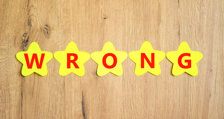 Wrong symbol. Concept word Wrong on beautiful yellow paper stars. Beautiful wooden table wooden...