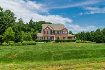 Obraz premium large traditional red brick colonial house on a green lawn in Virginia.