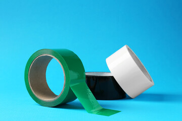 Rolls of different adhesive tapes on light blue background