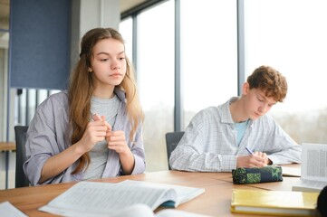 Fototapeta premium students sit at shared desk making notes studying together at university
