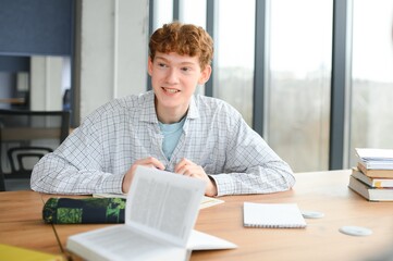 Portrait of smiling smart curly haired teenage boy holding book looking at camera. Back to school, Education concept © Serhii