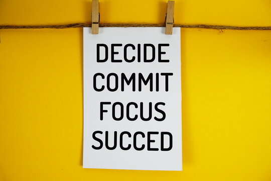 Decide Commit Focus Succeed text on paper card on yellow background