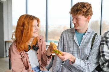 A group of young students having a lunch break together and eating sandwiches