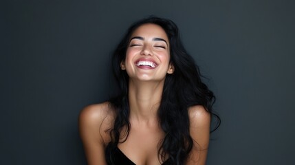 Portrait of happy latin young woman isolated on grey wall with copy space. Carefree hispanic woman smiling and looking at camera standing on gray background. Beautiful multiethnic girl laughing.