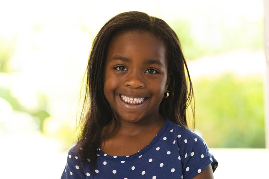 Smiling girl in polka dot shirt enjoying time at home, feeling happy