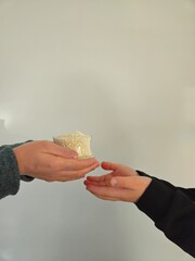 Ramadan, Hands holding a money bag for zakat, Islamic zakat concept. Closeup Hands giving bowl of rice for zakat fitrah. Conceptual photo for ‘zakat’ or ‘eidy’ on the occasion of Eid festival. Rice in