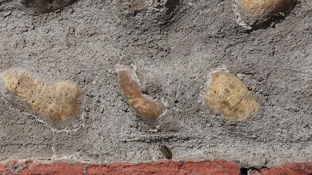Pierres incrust&eacute;es dans un mur de b&eacute;ton avec une punaise en exploration
