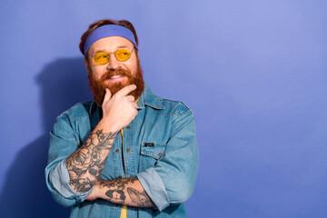 Trendy man with a beard and tattoos smiling confidently, wearing casual denim attire and yellow sunglasses