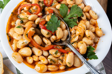 Lobio is a dish of Georgian, Azerbaijani and Armenian cuisines made from green bean pods. Lobio on a spoon. Traditional Georgian cuisine lobio. Lean dish. Lobio with pepper, onion. Side view.