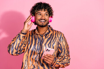 Young Stylish Man with Curly Hair Listening to Music on Pink Background